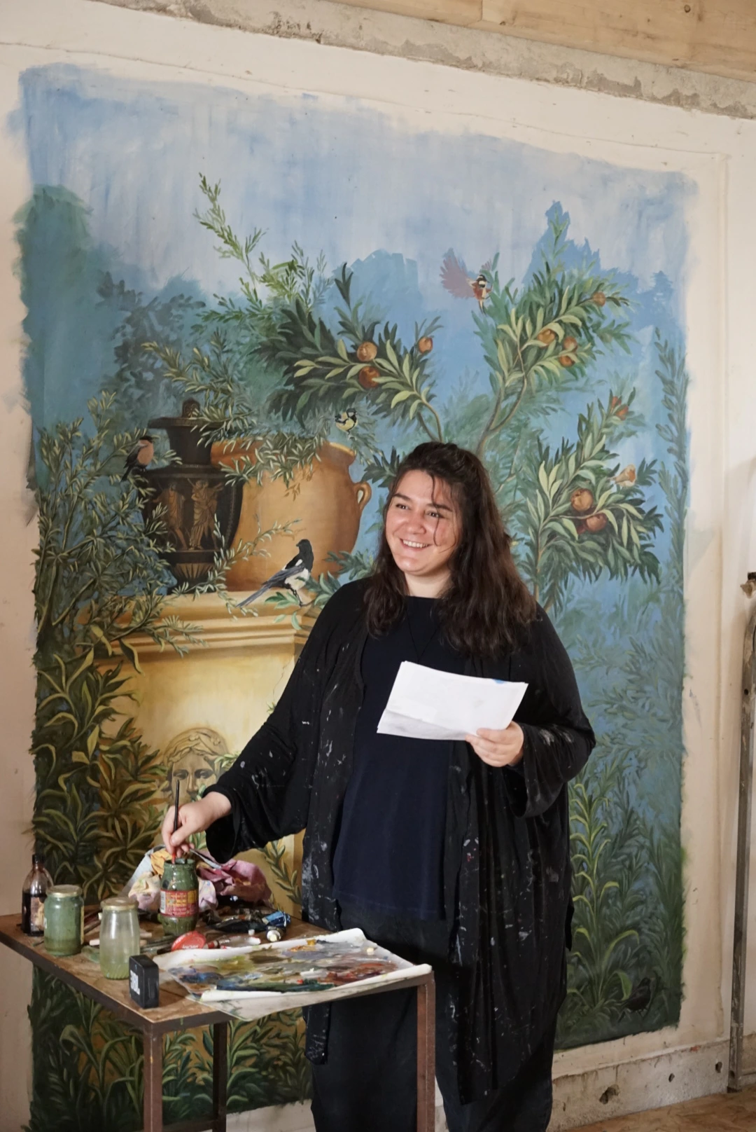Photo de l'artisane Agathe Saumet-Roche posant devant sa fresque "Villa Livia" Agathe Saumet-Roche